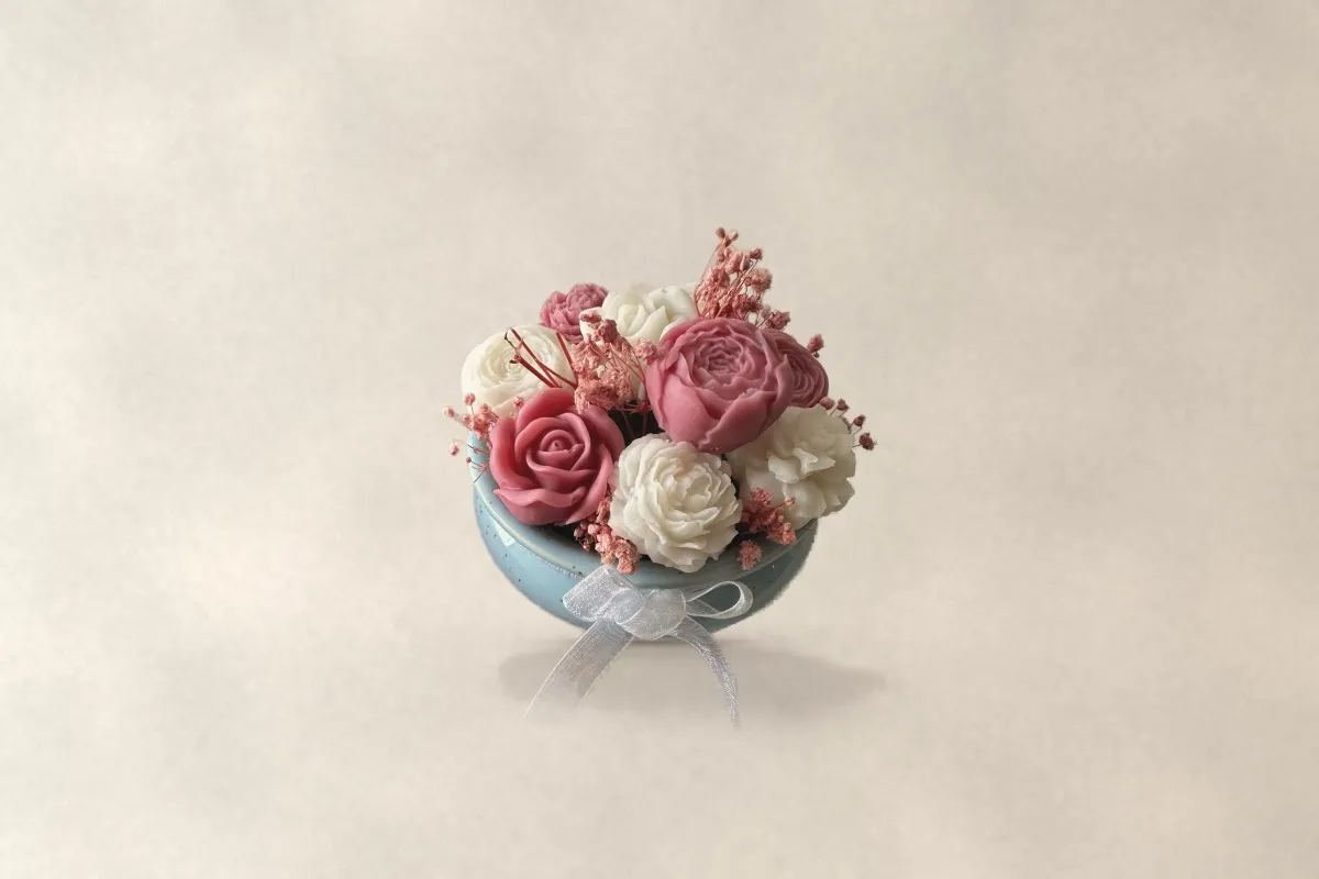 Pink and ivory wax roses in a pale blue pot, front view