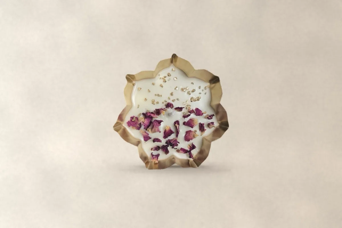 A flower-shaped gold urli filled with ivory wax and rose petals