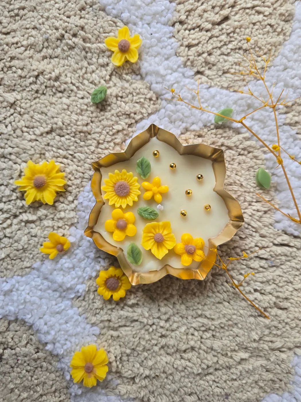 A sunflower urli candle surrounded by fresh flowers